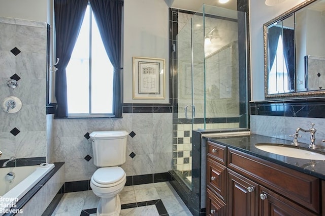 full bathroom with vanity, toilet, independent shower and bath, and tile walls