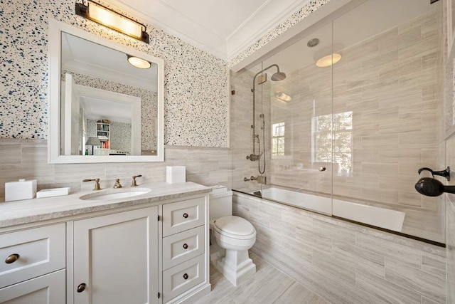 full bathroom with toilet, shower / bath combination with glass door, tile walls, ornamental molding, and vanity