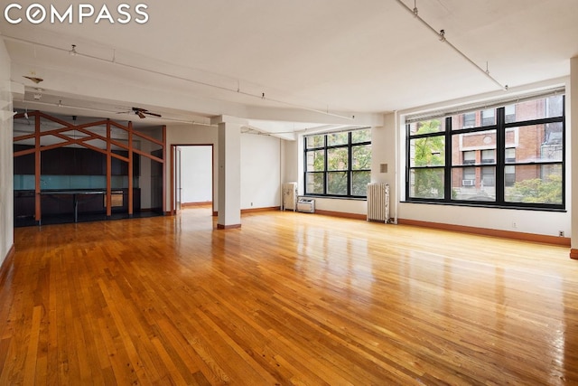 unfurnished room featuring ceiling fan, radiator, and light hardwood / wood-style flooring