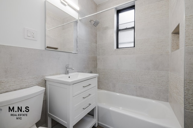 full bathroom featuring toilet, tile walls, vanity, and tiled shower / bath combo