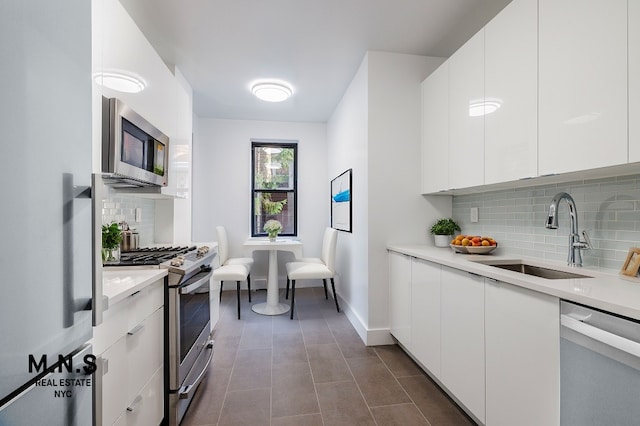 kitchen featuring white cabinets, appliances with stainless steel finishes, sink, and tasteful backsplash