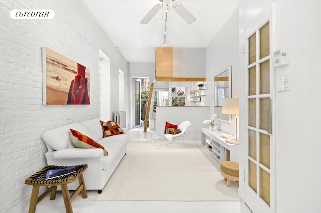 sitting room with brick wall, radiator, light colored carpet, and ceiling fan