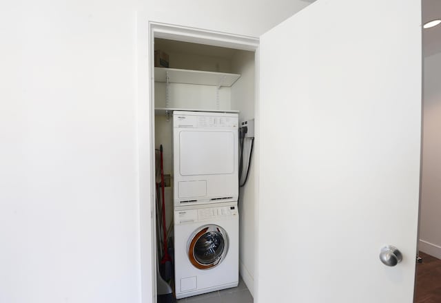 laundry area with stacked washer / drying machine and baseboards