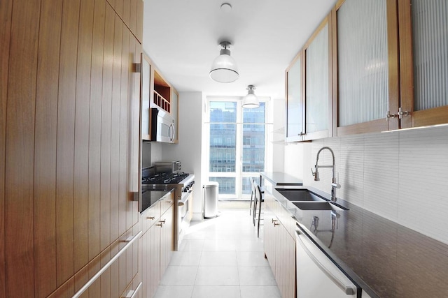 kitchen with white microwave, a sink, high end stainless steel range oven, dishwasher, and dark countertops