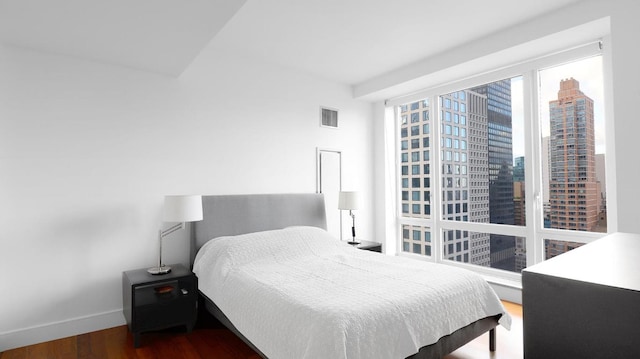 bedroom featuring a view of city, visible vents, dark wood finished floors, and baseboards