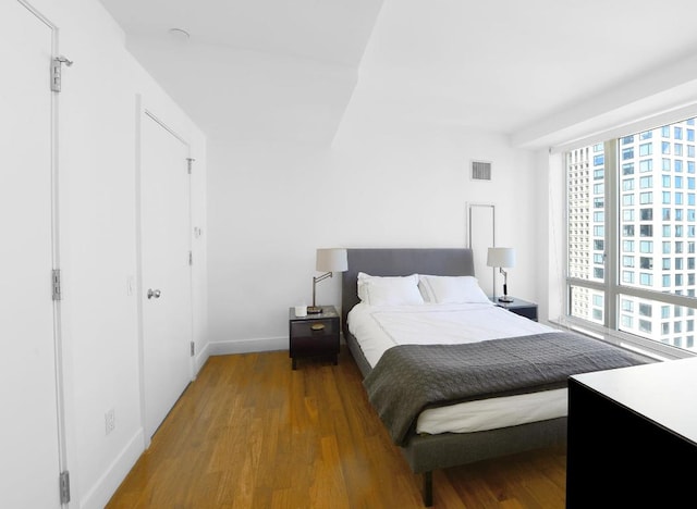 bedroom with visible vents, baseboards, and wood finished floors