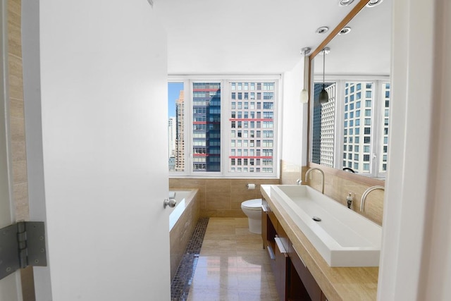 bathroom with a view of city, tile walls, toilet, vanity, and tile patterned flooring