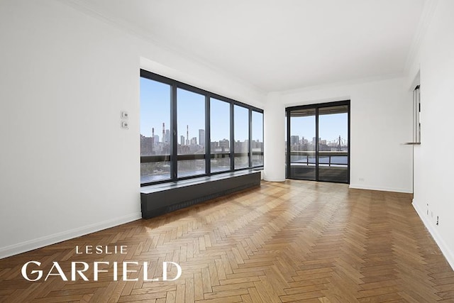 unfurnished room featuring ornamental molding, a city view, and baseboards