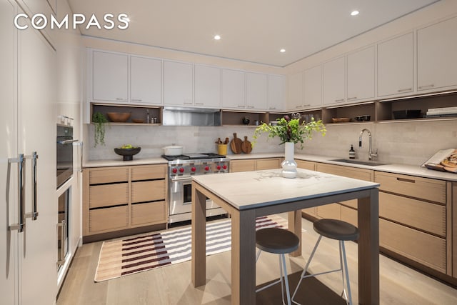 kitchen with wall oven, luxury stove, a sink, light countertops, and open shelves