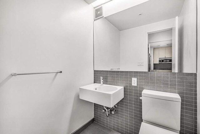 bathroom featuring vanity, toilet, tile patterned flooring, and decorative backsplash