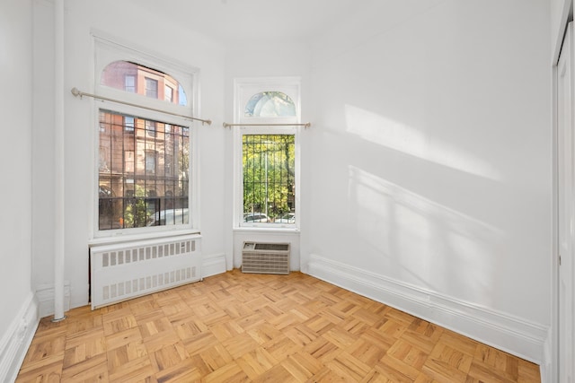 empty room with a wall unit AC, radiator heating unit, and baseboards