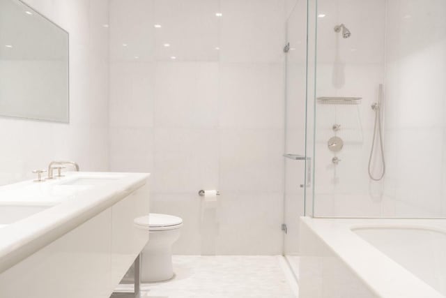 full bathroom featuring tile walls, toilet, vanity, and shower with separate bathtub