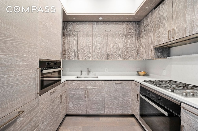 kitchen with stainless steel gas cooktop, ventilation hood, oven, and sink