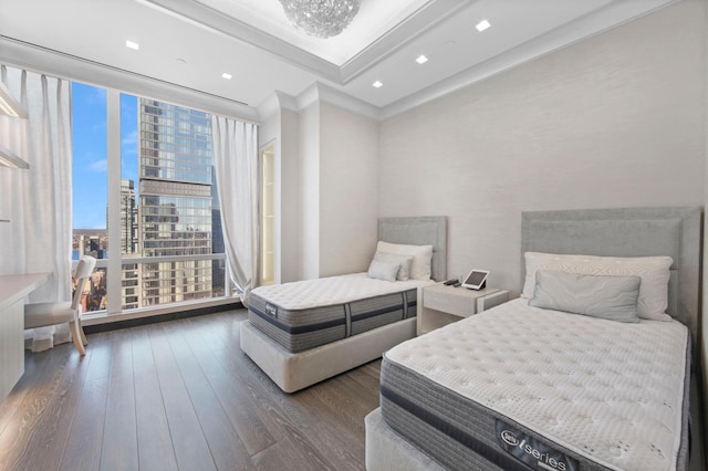 bedroom featuring hardwood / wood-style floors, a tray ceiling, and a wall of windows