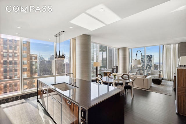 kitchen with a kitchen island with sink, dark wood-style flooring, floor to ceiling windows, a view of city, and open floor plan