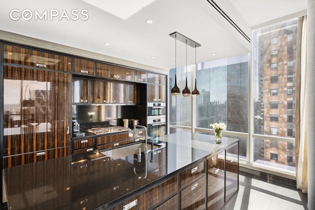 kitchen with modern cabinets, a sink, decorative light fixtures, dark stone counters, and dark brown cabinetry