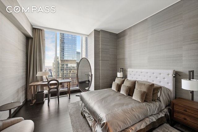 bedroom featuring a wall of windows, a view of city, and wood finished floors