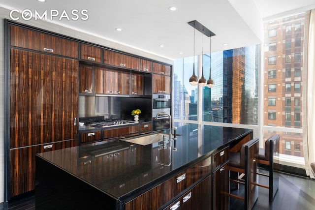 kitchen with modern cabinets, a large island with sink, a sink, and plenty of natural light