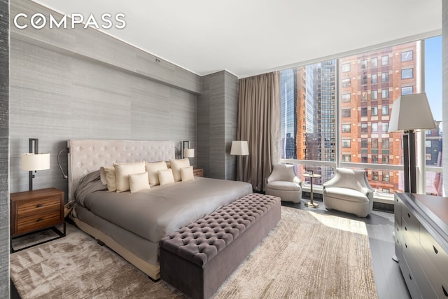 bedroom featuring a wall of windows and wood finished floors
