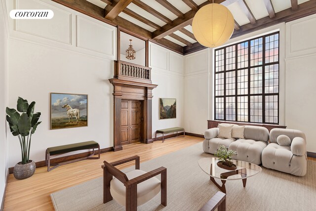 131 E 66th St Unit 8/9C, New York City, NY 10065 - unfurnished living room featuring radiator, a fireplace, wood-type flooring, built in shelves, and beamed ceiling
