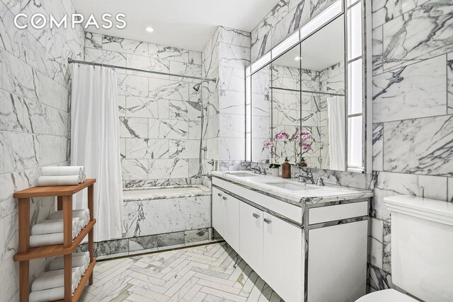 bathroom with a sink, toilet, tile walls, and a combined bath / shower with marble appearance