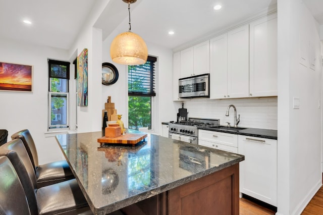 kitchen with backsplash, appliances with stainless steel finishes, white cabinets, and a sink