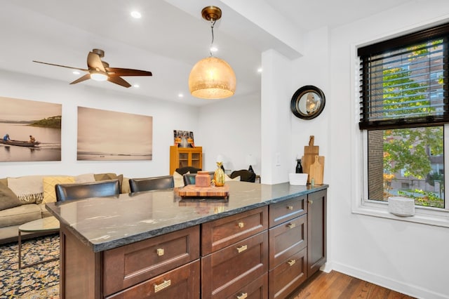 9707 4th Ave Unit 3R, New York City, NY 11220 - kitchen with wood finished floors, dark stone countertops, open floor plan, a ceiling fan, and hanging light fixtures