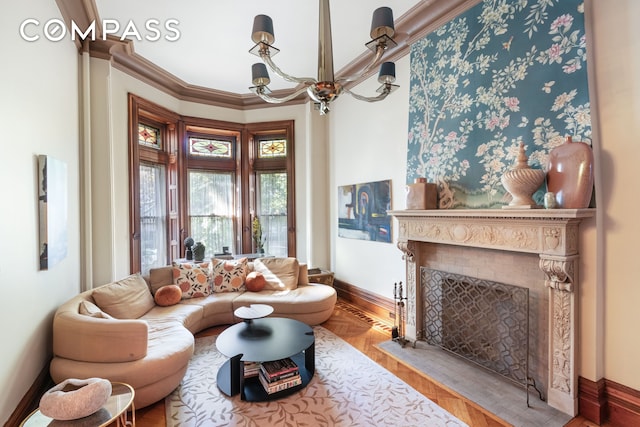 living area featuring a fireplace with flush hearth, baseboards, an inviting chandelier, and ornamental molding