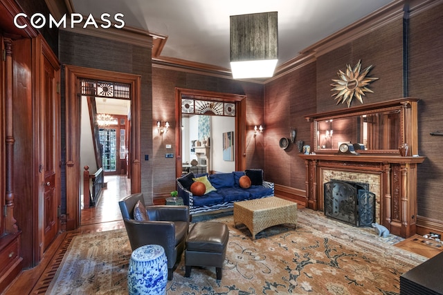 living area with crown molding, a brick fireplace, wood finished floors, and baseboards