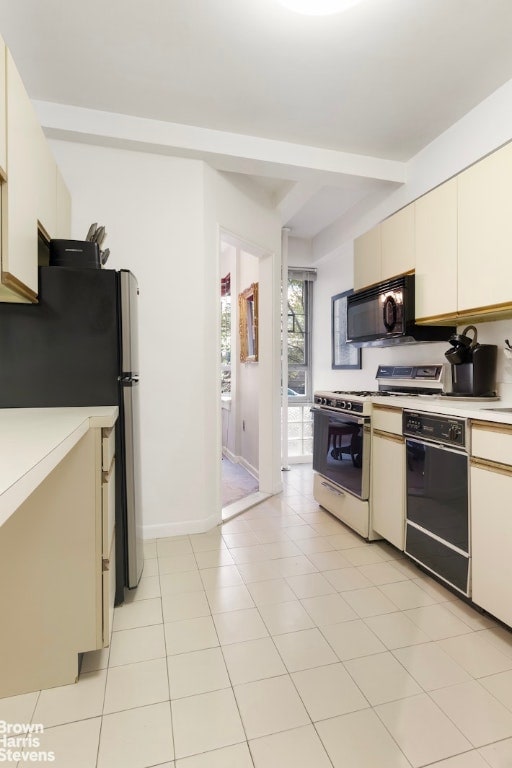 kitchen featuring black appliances, light tile patterned floors, and cream cabinetry