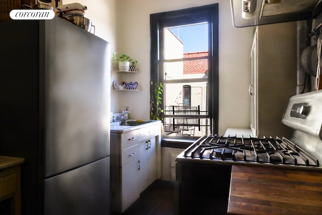 kitchen with freestanding refrigerator, range with gas cooktop, dark wood-style flooring, and a sink