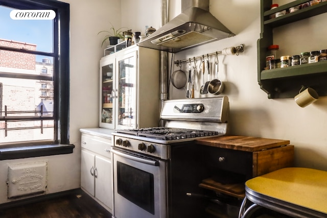 kitchen featuring stainless steel gas range, extractor fan, white cabinets, dark wood-type flooring, and light countertops