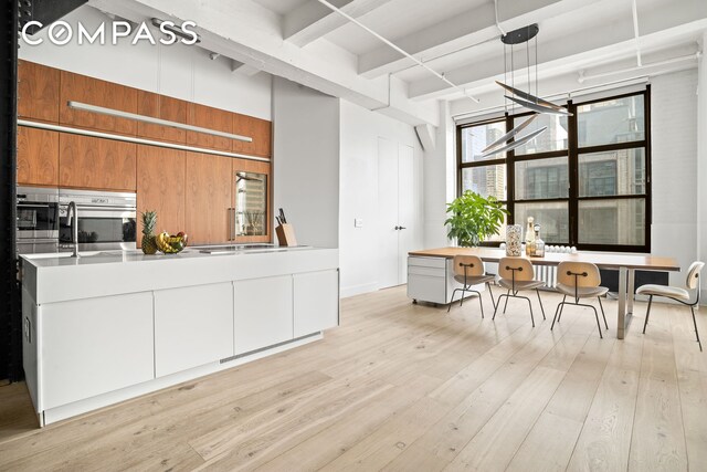 kitchen with white cabinetry, oven, and light hardwood / wood-style floors