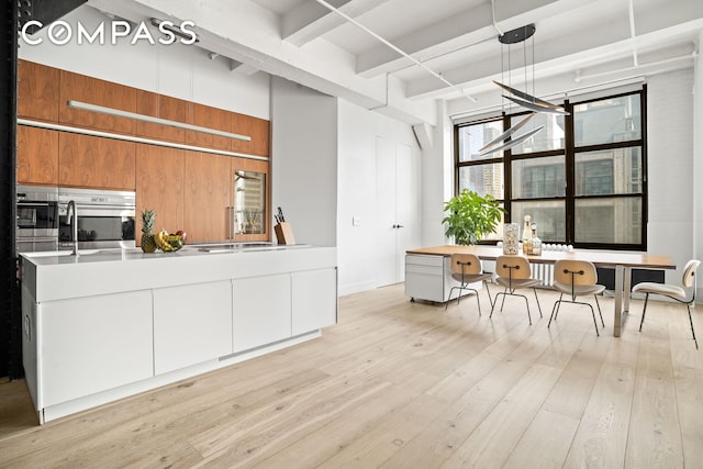 448 W 37th St Unit 8C, New York City, NY 10018 - kitchen featuring beam ceiling, a desk, light wood-style flooring, light countertops, and wooden walls