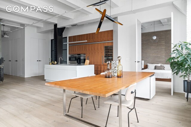 dining space featuring sink, a towering ceiling, and light wood-type flooring