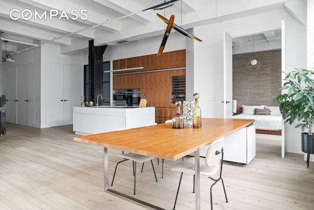 448 W 37th St Unit 8C, New York City, NY 10018 - dining room with a towering ceiling, light wood-style flooring, and beamed ceiling
