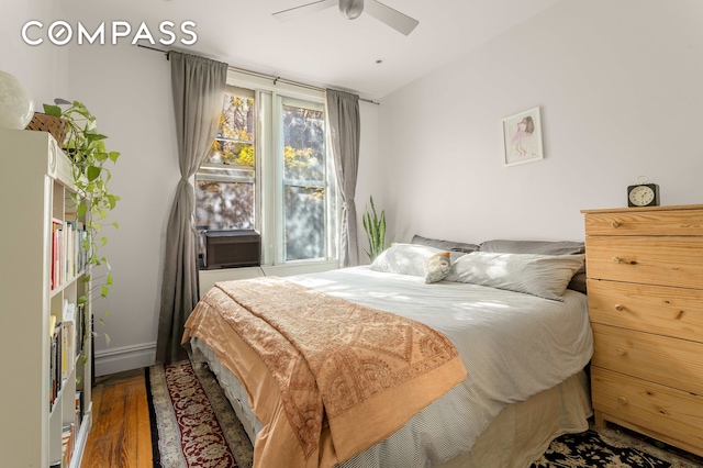 bedroom featuring ceiling fan, cooling unit, wood finished floors, and baseboards