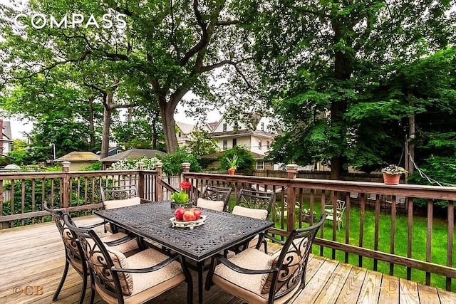 wooden deck featuring fence, outdoor dining area, and a lawn