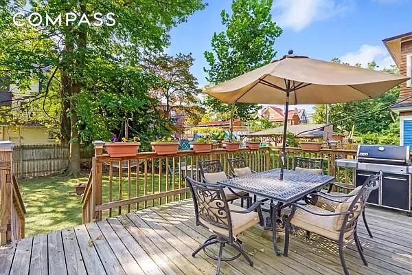 wooden terrace with outdoor dining space, fence, and area for grilling