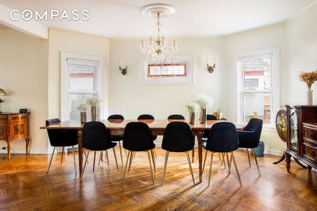 dining space with parquet flooring, a healthy amount of sunlight, and a notable chandelier