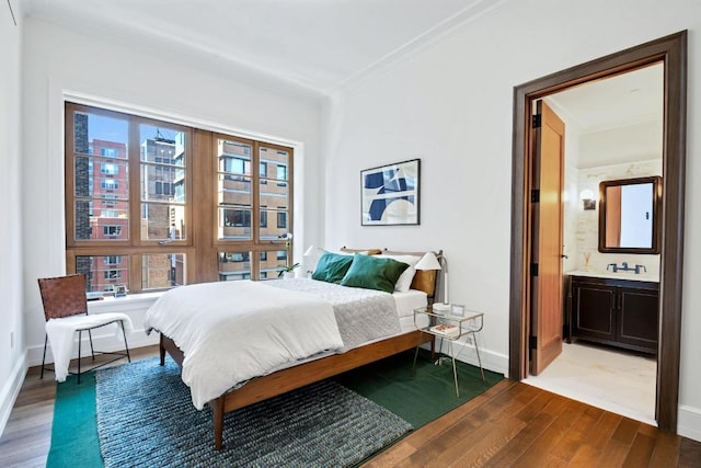 bedroom with hardwood / wood-style flooring, ensuite bath, crown molding, and sink