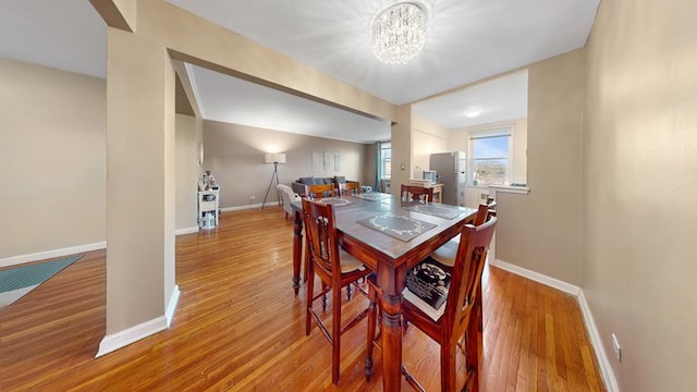 dining area featuring a notable chandelier, baseboards, and wood finished floors