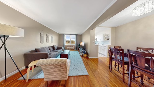 living room with ornamental molding, a chandelier, and light wood-type flooring