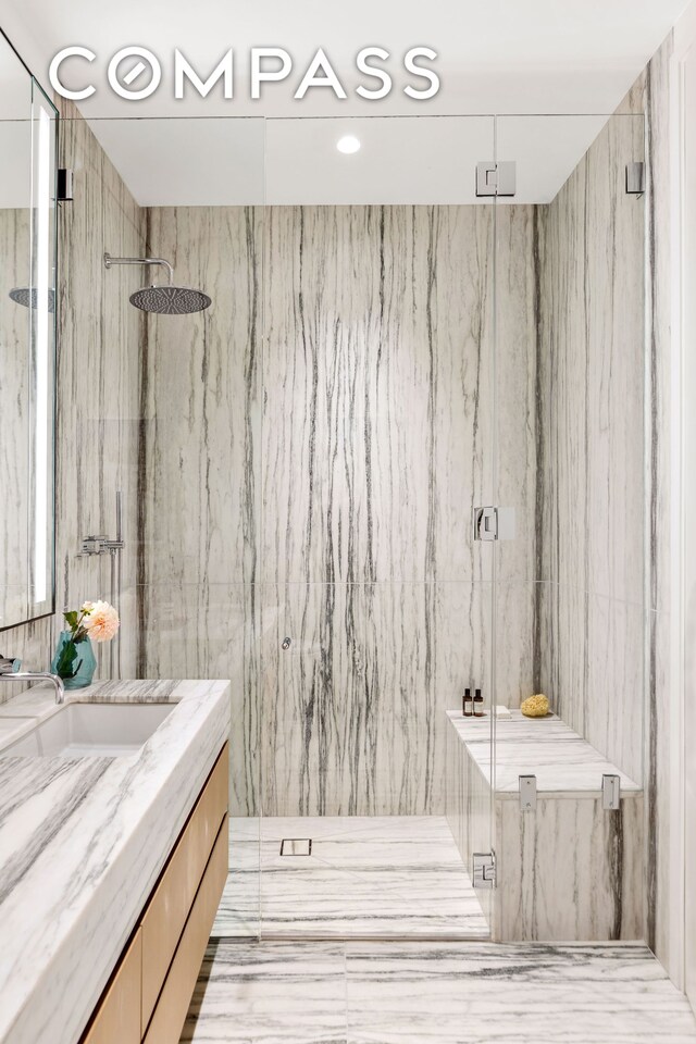 bathroom featuring vanity and a marble finish shower