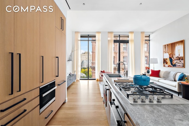 kitchen featuring stainless steel gas cooktop, a sink, light wood finished floors, and modern cabinets