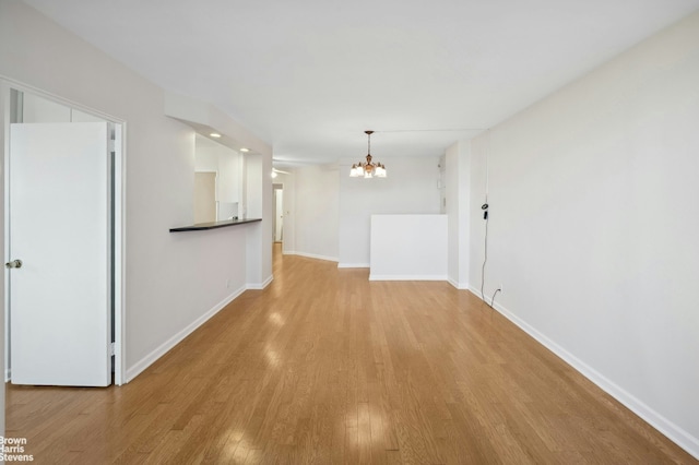 interior space with baseboards, an inviting chandelier, and wood finished floors