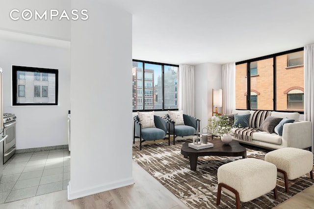 living room with expansive windows, baseboards, and light wood-style floors