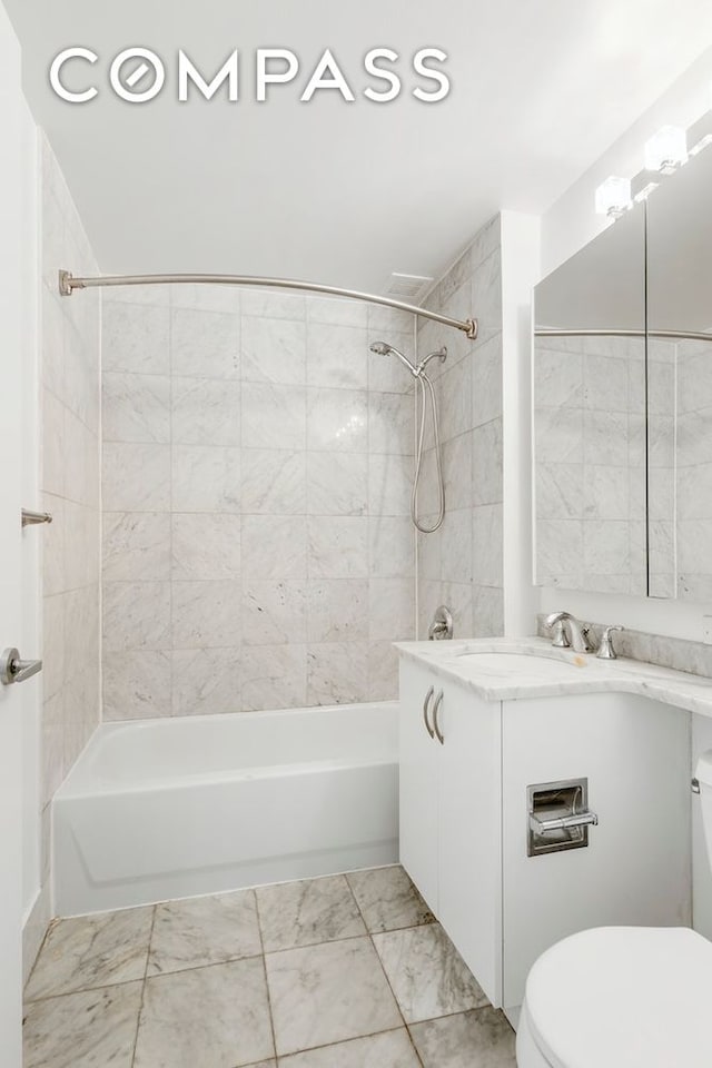 bathroom featuring marble finish floor, vanity, toilet, and bathtub / shower combination