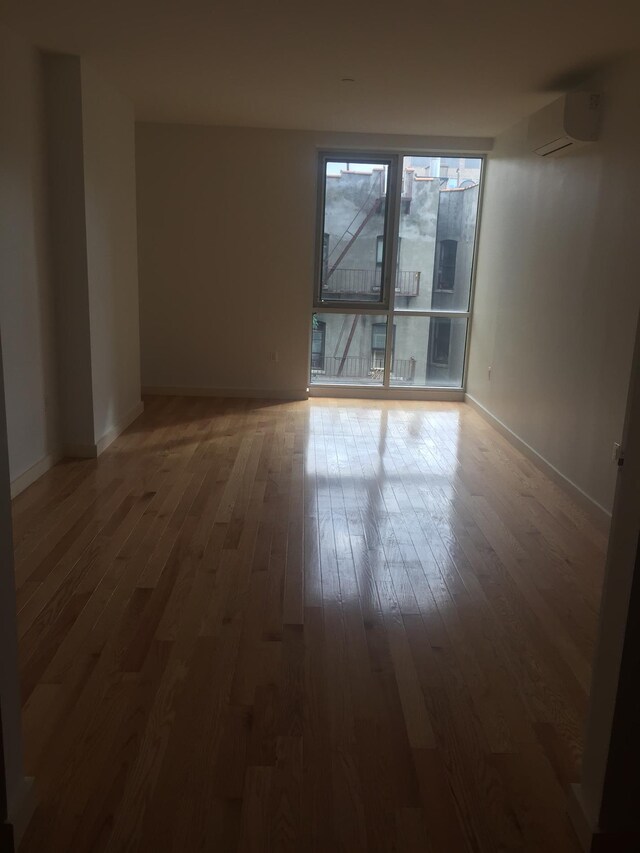 spare room with an AC wall unit and dark hardwood / wood-style flooring