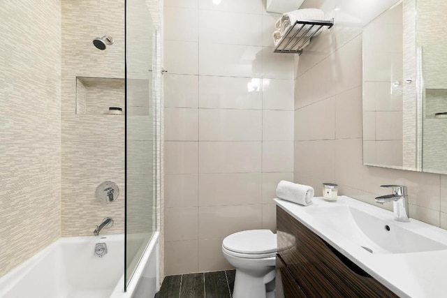 full bathroom featuring tile walls, vanity, tiled shower / bath combo, and toilet